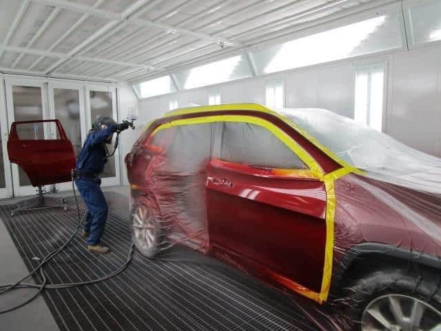 a Bates Collision team member painting a car red